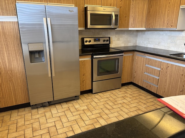 kitchen with tasteful backsplash, sink, and appliances with stainless steel finishes