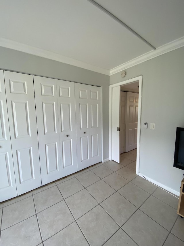 unfurnished bedroom featuring light tile patterned floors, a closet, and ornamental molding