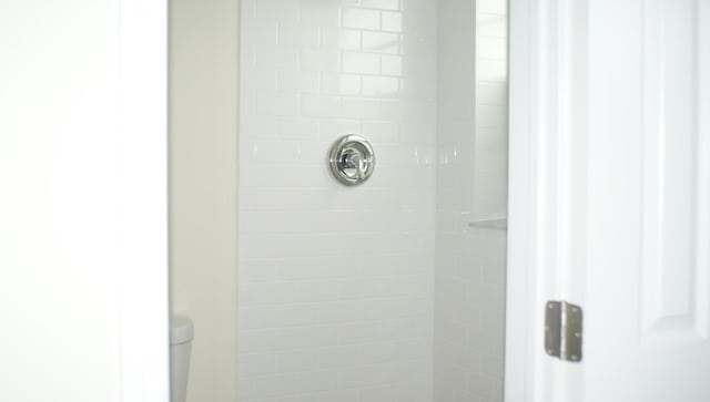 interior details featuring a tile shower and toilet