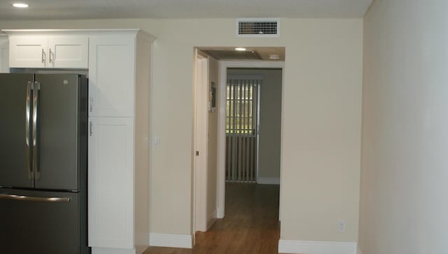 kitchen with white cabinets, stainless steel fridge, and dark wood-type flooring