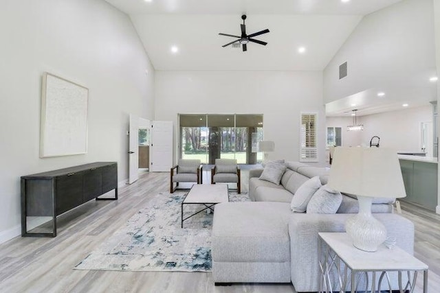 living room featuring ceiling fan, high vaulted ceiling, and light hardwood / wood-style floors