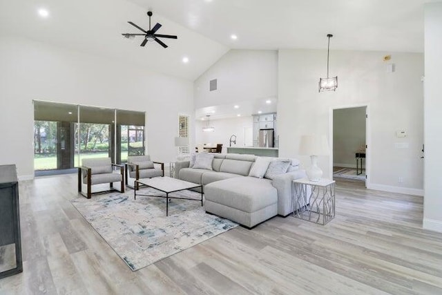 living room with ceiling fan, light hardwood / wood-style floors, and high vaulted ceiling