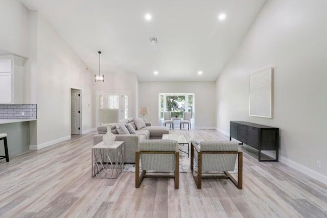 living room with light hardwood / wood-style floors, high vaulted ceiling, and a chandelier