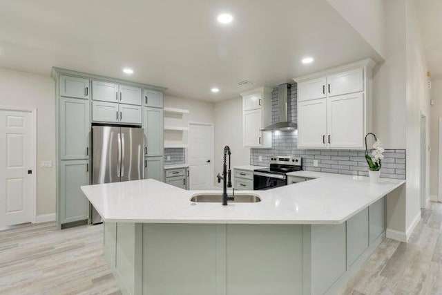 kitchen featuring sink, wall chimney exhaust hood, appliances with stainless steel finishes, tasteful backsplash, and kitchen peninsula