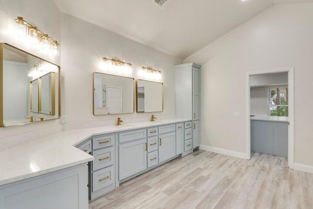 bathroom with hardwood / wood-style floors, vanity, and vaulted ceiling