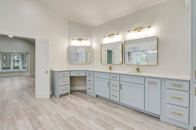 bathroom with hardwood / wood-style floors, vanity, and vaulted ceiling