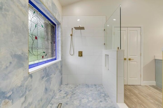 bathroom with a tile shower, vanity, and wood-type flooring