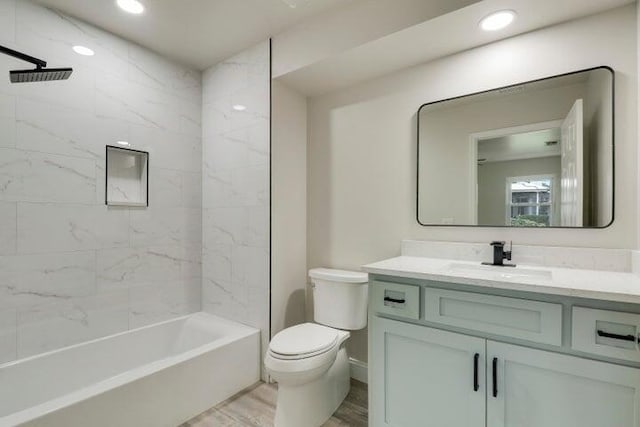 full bathroom featuring tiled shower / bath, vanity, wood-type flooring, and toilet