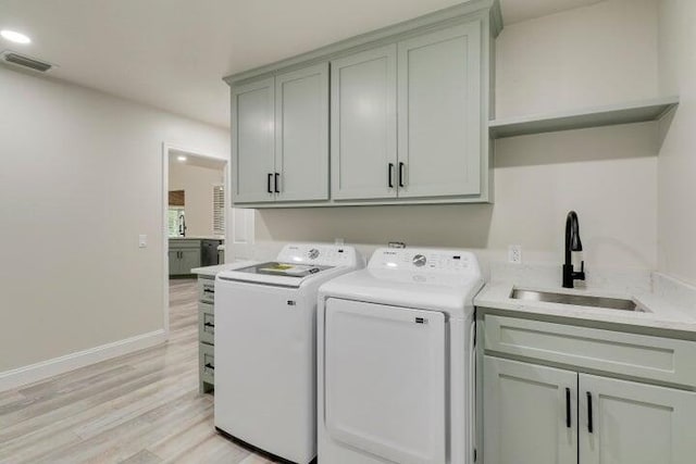 laundry area featuring sink, light hardwood / wood-style flooring, cabinets, and independent washer and dryer