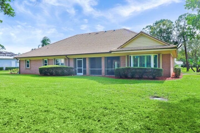 rear view of property with a yard and a sunroom