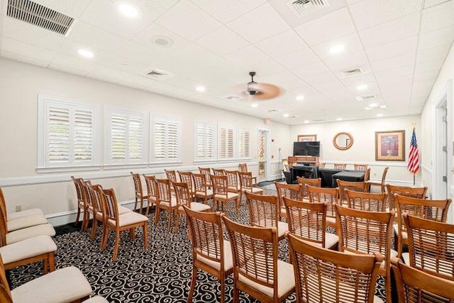 carpeted dining area with ceiling fan and a drop ceiling