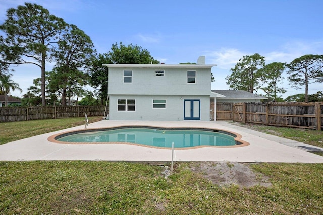 view of pool with french doors, a patio area, and a lawn