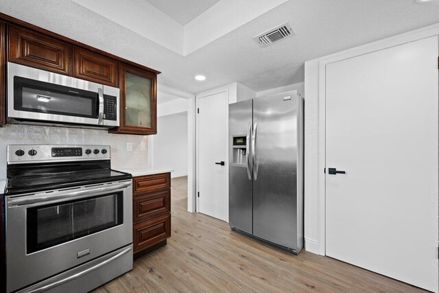 kitchen featuring a wealth of natural light, light hardwood / wood-style floors, kitchen peninsula, and appliances with stainless steel finishes