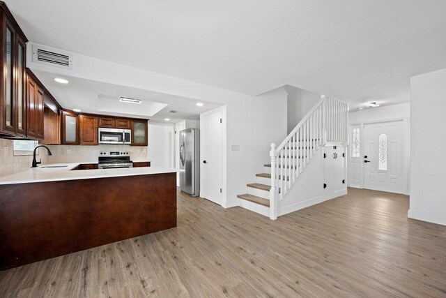 kitchen featuring kitchen peninsula, stainless steel appliances, a healthy amount of sunlight, and light hardwood / wood-style floors