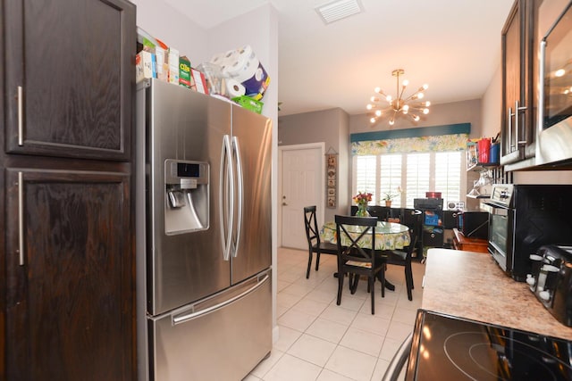 kitchen featuring light tile patterned flooring, dark brown cabinetry, stainless steel appliances, and a notable chandelier