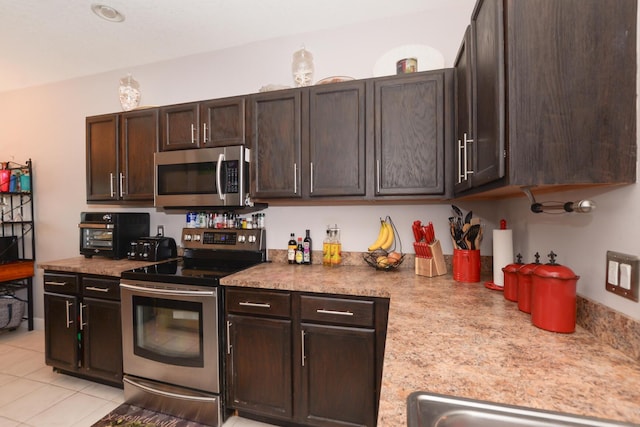 kitchen featuring light tile patterned flooring, dark brown cabinetry, stainless steel appliances, and sink