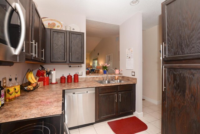 kitchen featuring stainless steel appliances, dark brown cabinets, sink, and light tile patterned floors