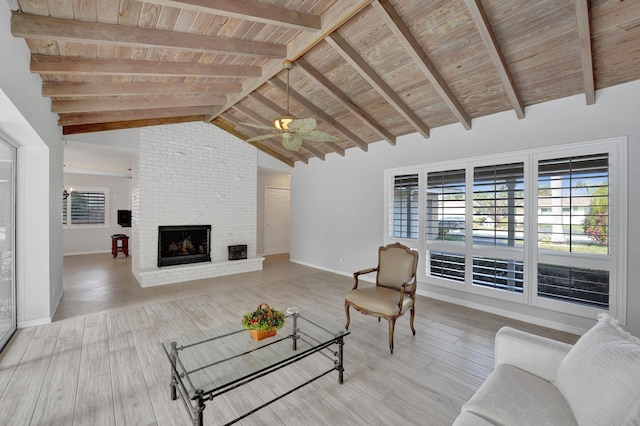 living room with ceiling fan, wooden ceiling, a brick fireplace, light hardwood / wood-style flooring, and beamed ceiling