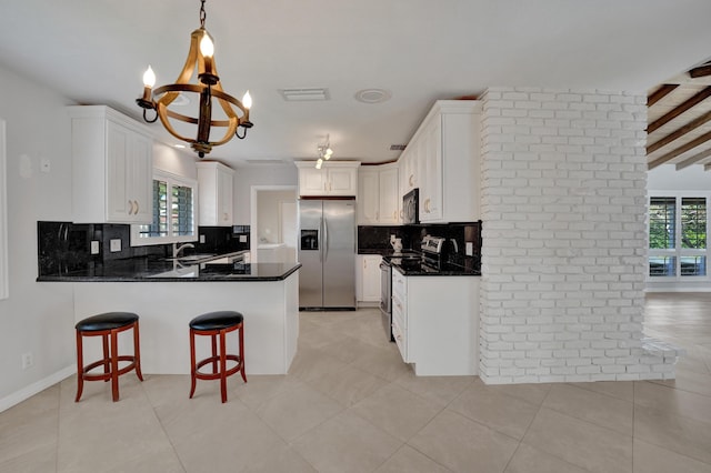 kitchen featuring beamed ceiling, kitchen peninsula, a chandelier, white cabinets, and appliances with stainless steel finishes