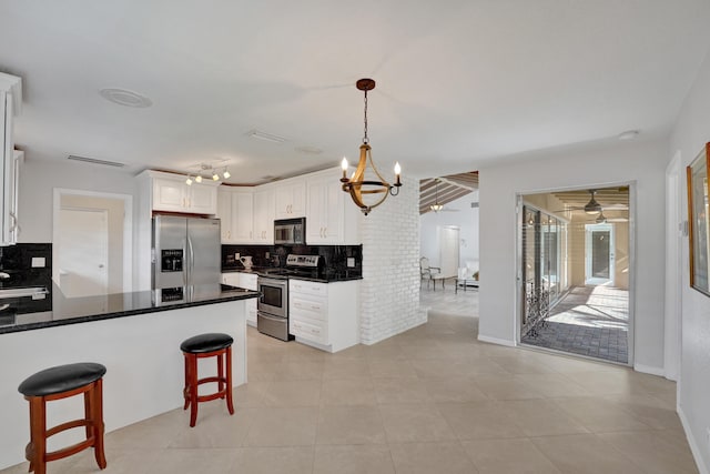 kitchen featuring white cabinetry, hanging light fixtures, stainless steel appliances, tasteful backsplash, and kitchen peninsula