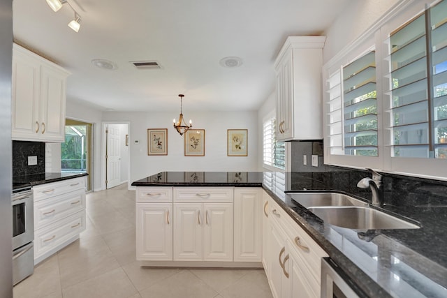 kitchen with a chandelier, sink, white cabinetry, and dark stone countertops