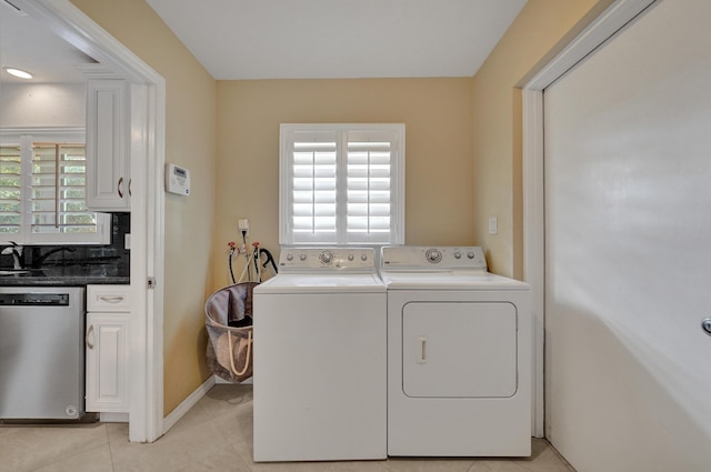 washroom featuring plenty of natural light, washing machine and dryer, light tile patterned floors, and sink