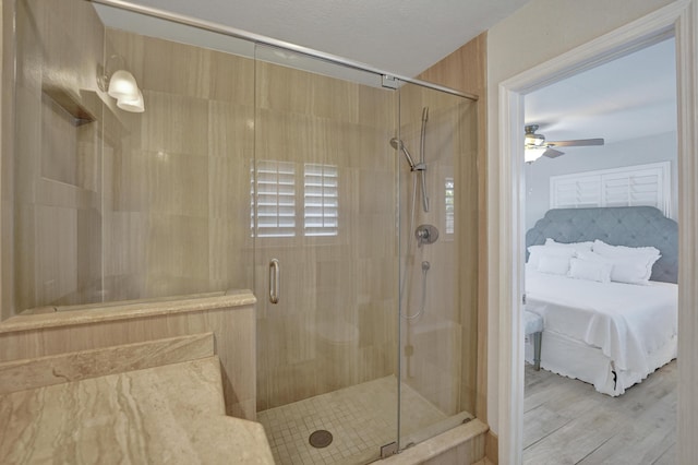 bathroom featuring ceiling fan, an enclosed shower, and wood-type flooring