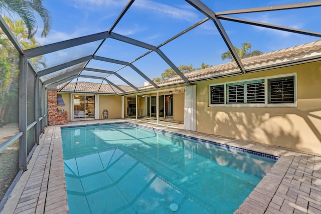 view of swimming pool featuring glass enclosure, ceiling fan, and a patio area