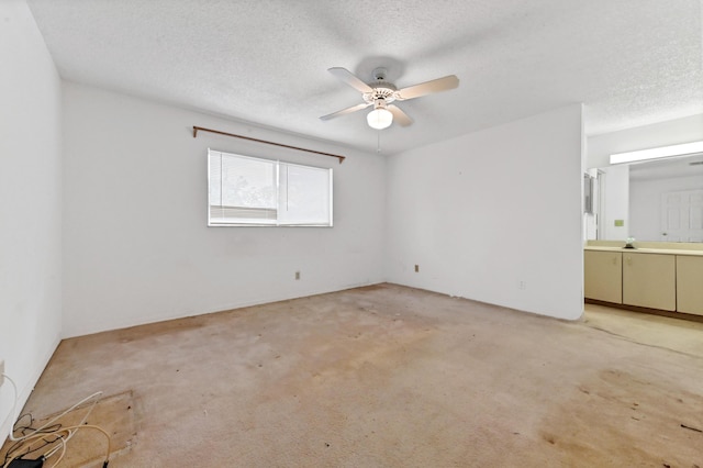 carpeted empty room with ceiling fan and a textured ceiling