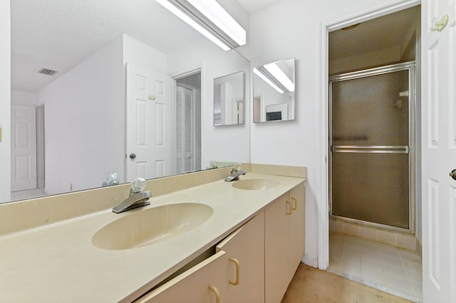 bathroom with a shower with door, vanity, and tile patterned flooring