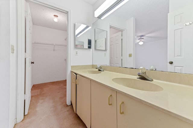 bathroom with ceiling fan, vanity, and a textured ceiling