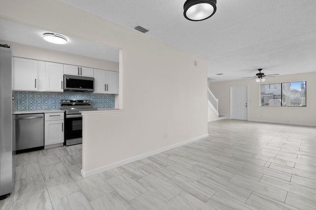 kitchen with white cabinets, ceiling fan, decorative backsplash, and appliances with stainless steel finishes