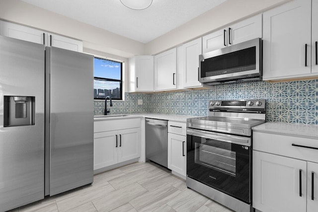 kitchen featuring stainless steel appliances, white cabinetry, tasteful backsplash, and sink