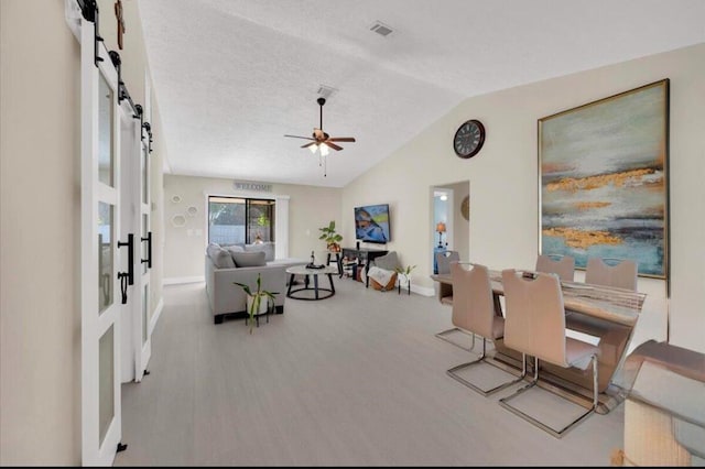 interior space featuring ceiling fan, lofted ceiling, a textured ceiling, and light hardwood / wood-style flooring