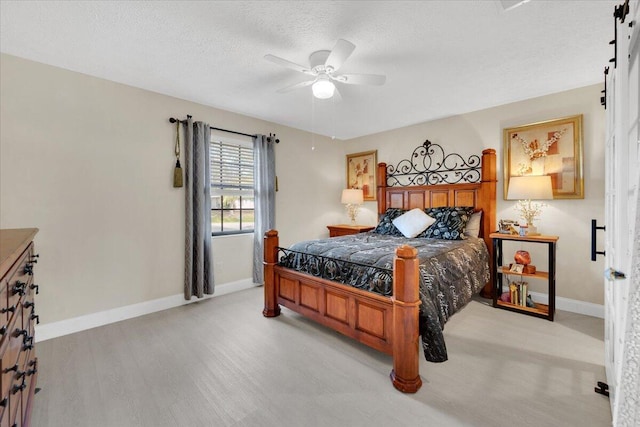 bedroom with ceiling fan, light hardwood / wood-style floors, and a textured ceiling