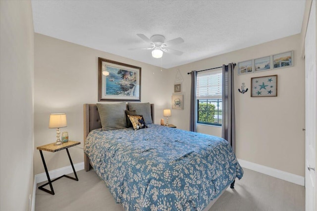 bedroom featuring ceiling fan, light colored carpet, and a textured ceiling