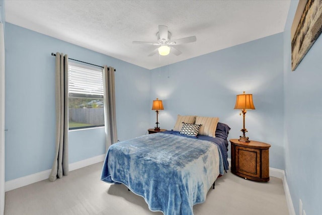 bedroom featuring ceiling fan, light carpet, and a textured ceiling