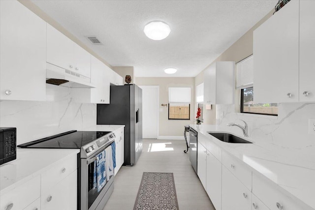 kitchen with sink, stainless steel appliances, a textured ceiling, decorative backsplash, and white cabinets