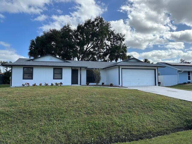 ranch-style home with a garage and a front lawn