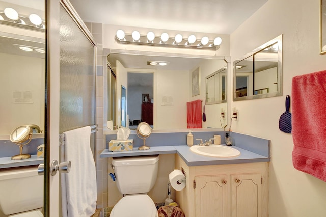 bathroom featuring a shower with door, vanity, and toilet