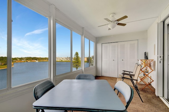 sunroom featuring ceiling fan and a water view