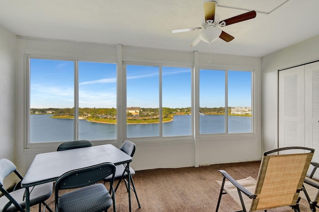 sunroom / solarium with ceiling fan, a water view, and plenty of natural light