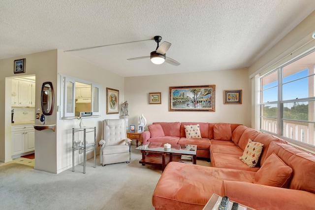 living room featuring ceiling fan, light colored carpet, and a textured ceiling