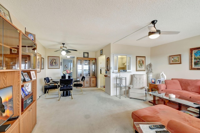 living room featuring a textured ceiling, ceiling fan, and light carpet