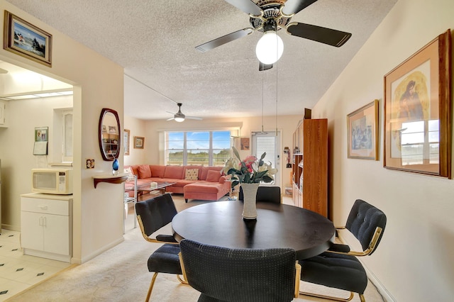 carpeted dining room featuring a textured ceiling and ceiling fan