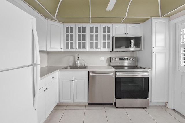 kitchen with white cabinets, appliances with stainless steel finishes, light tile patterned floors, and sink