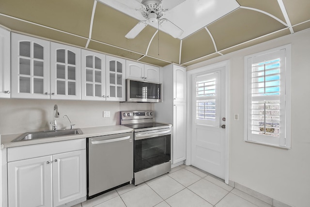 kitchen with stainless steel appliances, ceiling fan, sink, white cabinetry, and light tile patterned flooring