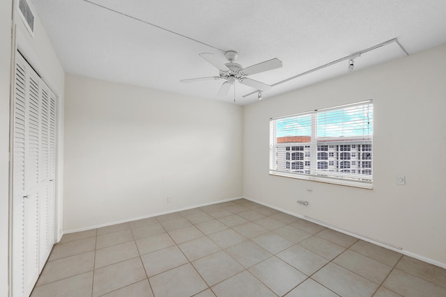 unfurnished bedroom featuring a textured ceiling, a closet, ceiling fan, and light tile patterned flooring