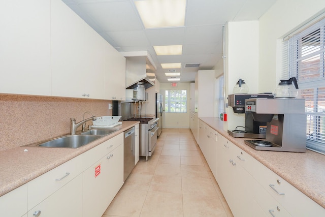 kitchen with light tile patterned flooring, appliances with stainless steel finishes, white cabinetry, and sink