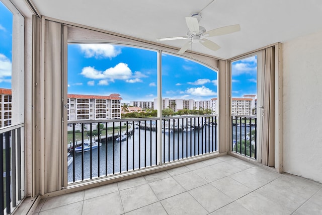 unfurnished sunroom featuring a water view and ceiling fan